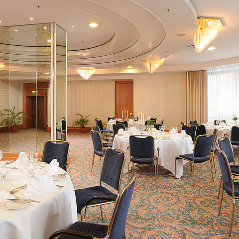 Salon Dresden im Maritim Hotel Magdeburg mit eleganten, weiß gedeckten Tischen, Kerzenleuchtern und stilvoller Beleuchtung für festliche Anlässe.