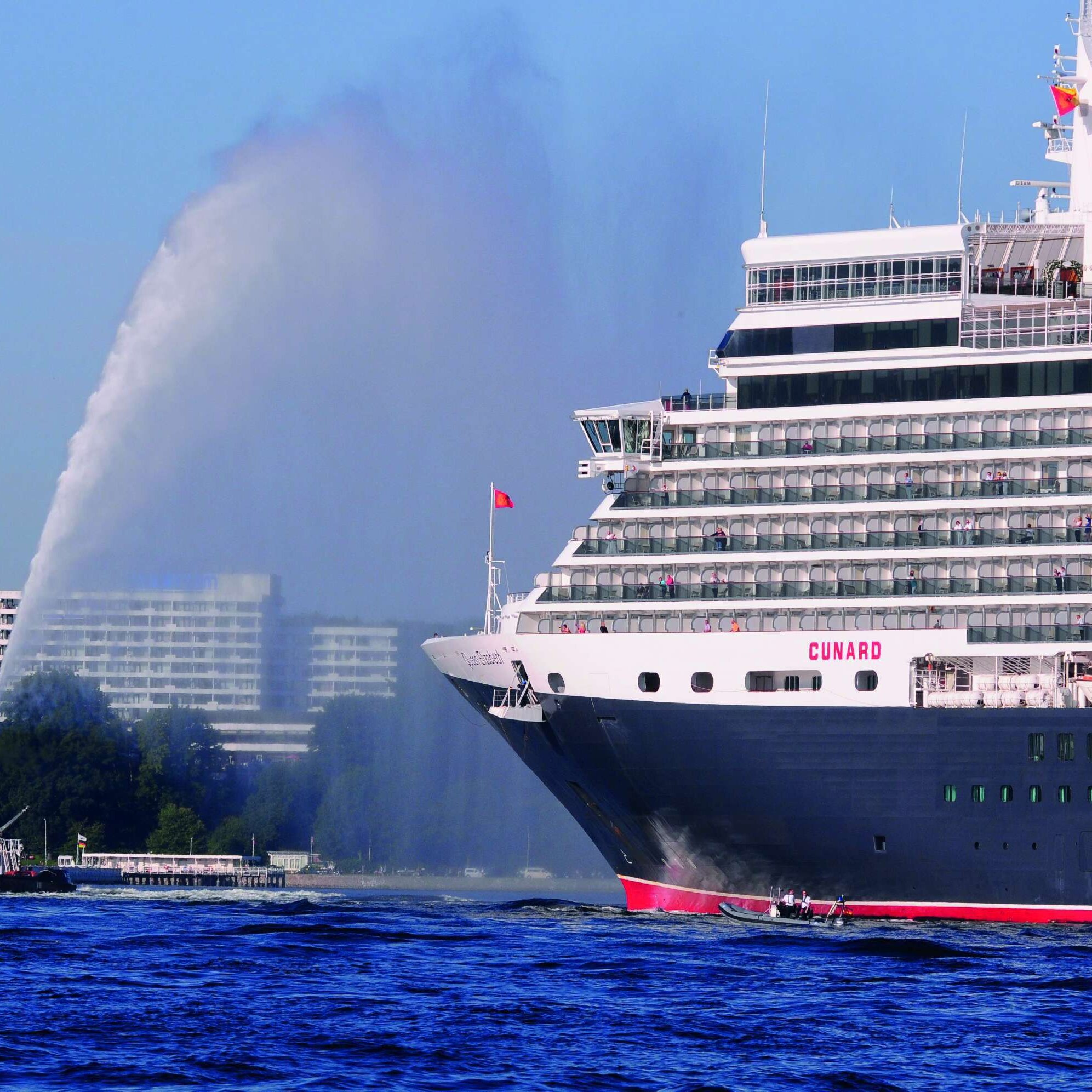 Außenansicht des Maritim Hotels Kiel, im Vordergrund das Kreuzfahrtschiff Queen Elizabeth und ein Schlepper auf dem Wasser.