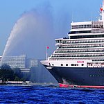 Außenansicht des Maritim Hotels Kiel, im Vordergrund das Kreuzfahrtschiff Queen Elizabeth und ein Schlepper auf dem Wasser.