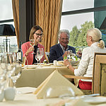 Fröhliche Gäste genießen ein Glas Wein und ein Essen im Restaurant des Maritim Hotel Dresden.