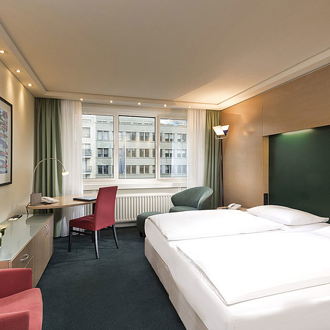 Classic Zimmer im Maritim proArte Hotel Berlin mit Doppelbett, Schreibtisch und Blick auf umliegende Gebäude.