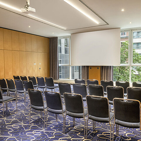 Moderner Tagungsraum im Maritim proArte Hotel Berlin mit Stuhlreihen und Leinwand.