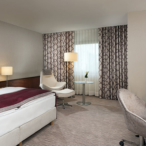 Comfort Zimmer im Maritim Hotel Bonn mit gemütlichem Bett, Sesseln, Schreibtisch und modernen Vorhängen.