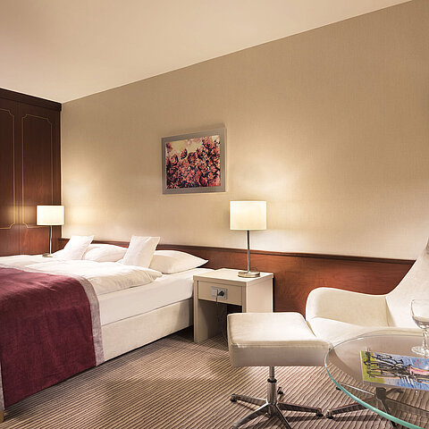 Classic Zimmer im Maritim Hotel Bonn, gemütlich eingerichtet mit Doppelbett, Sessel, Tisch und moderner Beleuchtung.