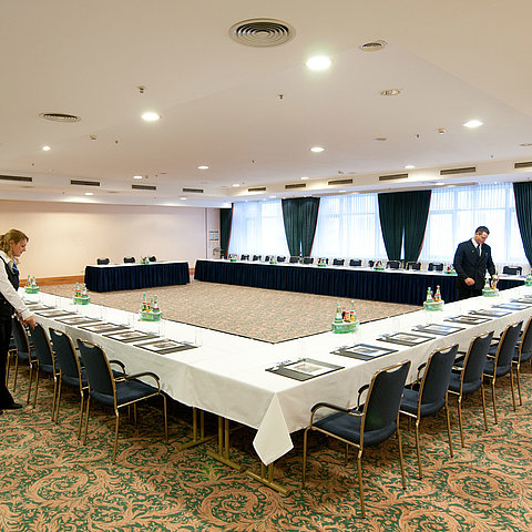 Tagungsraum Saal Berlin im Maritim Hotel Magdeburg mit U-förmiger Bestuhlung, gedeckten Tischen und Vorbereitung durch das Personal.