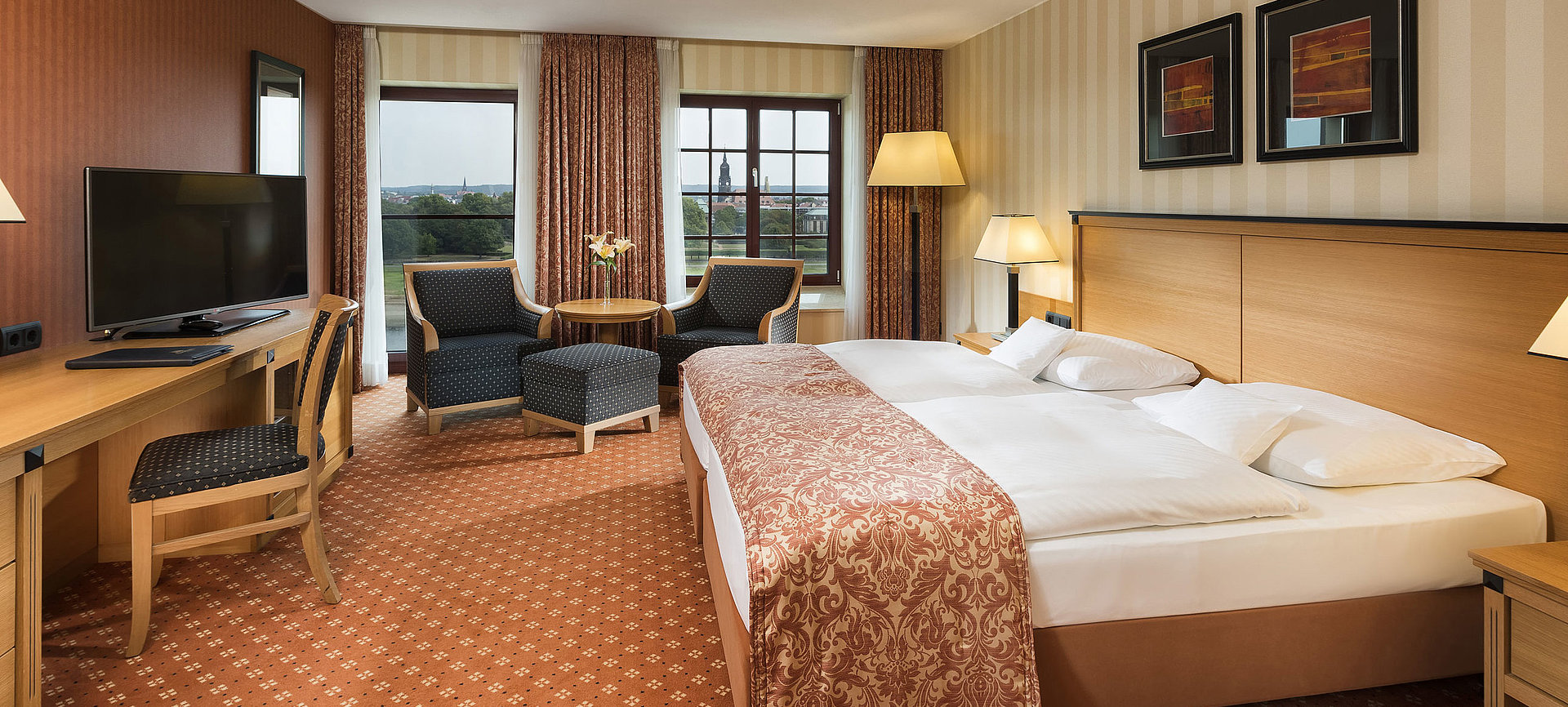 Superior Zimmer im Maritim Hotel Dresden mit elegantem Doppelbett, Schreibtisch und Sitzbereich sowie Blick auf die Stadt.