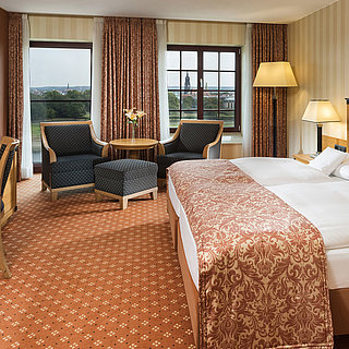 Superior Zimmer im Maritim Hotel Dresden mit elegantem Doppelbett, Schreibtisch und Sitzbereich sowie Blick auf die Stadt.