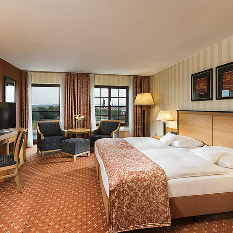 Superior Zimmer im Maritim Hotel Dresden mit elegantem Doppelbett, Schreibtisch und Sitzbereich sowie Blick auf die Stadt.