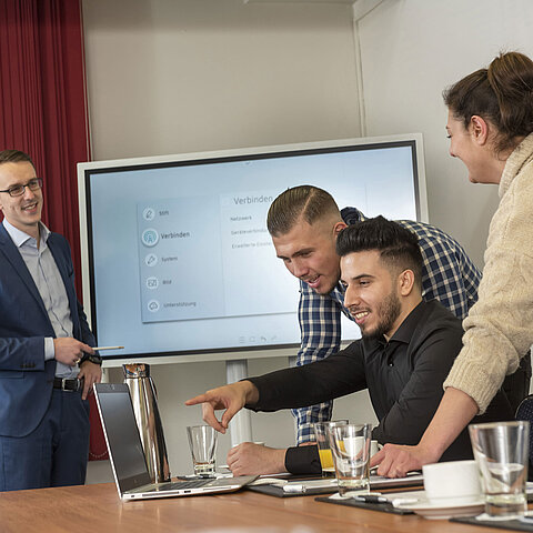 Team-Meeting im Salon Rhein im Maritim Köln mit einem Bildschirm, Laptops und Teilnehmern, die zusammenarbeiten.