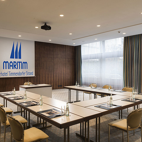 Konferenzraum „Salon Köln“ im Maritim Seehotel Timmendorfer Strand mit U-förmiger Bestuhlung und Tageslicht.