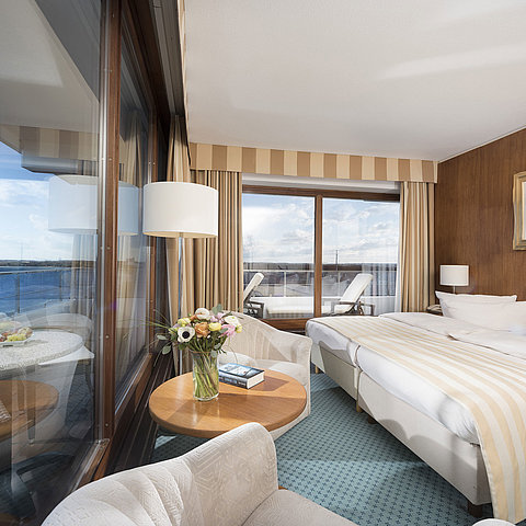 Superior Zimmer im Maritim Seehotel Timmendorfer Strand mit Meerblick, Doppelbett, Sitzecke und Balkon.