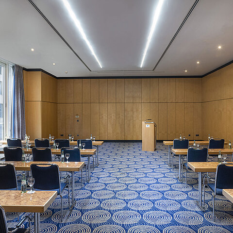 Tagungsraum Salon IV im Maritim proArte Hotel Berlin mit Tischen, Stühlen und Rednerpult.