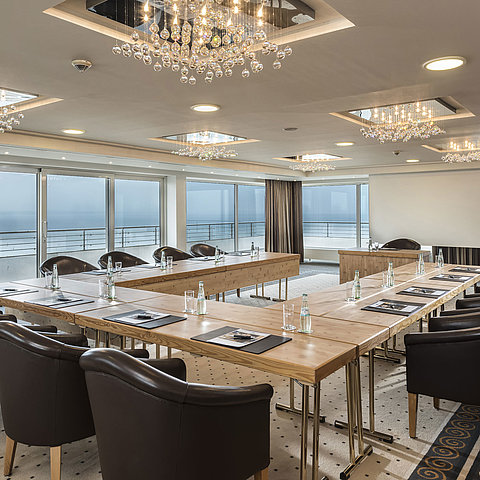 Salon Hamburg im Maritim Seehotel Timmendorfer Strand, Tagungsraum mit Meerblick, L-förmiger Tisch und eleganter Beleuchtung.