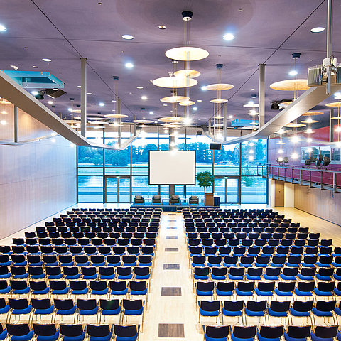 Großer Konferenzsaal im Maritim Hotel Dresden mit Reihen blauer Stühle und Blick auf die Elbe.