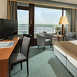 Superior Zimmer im Maritim Hotel Kiel mit Schreibtisch, Sitzbereich, großem Doppelbett und Balkon mit Blick auf die Förde.