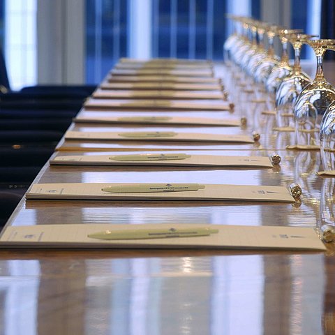 Nahaufnahme eines vorbereiteten Konferenztisches im Maritim proArte Hotel Berlin, mit Notizblöcken und Weingläsern.