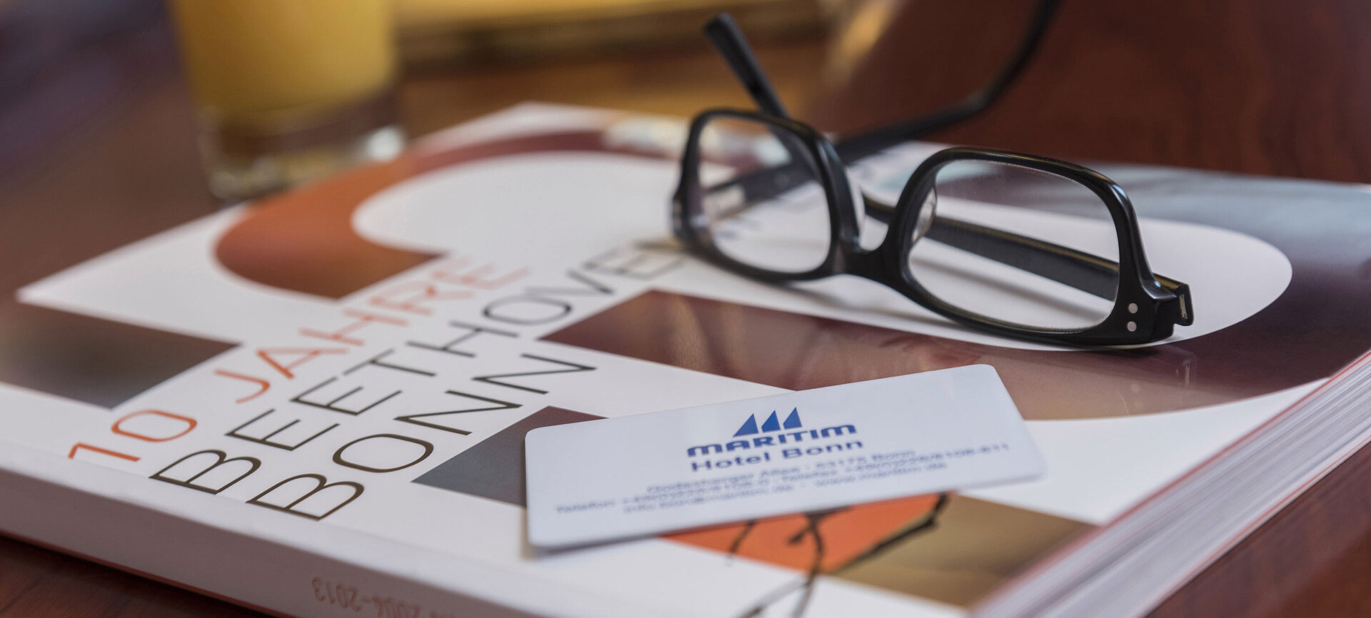 Detailaufnahme aus einem Zimmer im Maritim Hotel Bonn mit Brille, Hotelkarte und einem Buch über Beethoven.