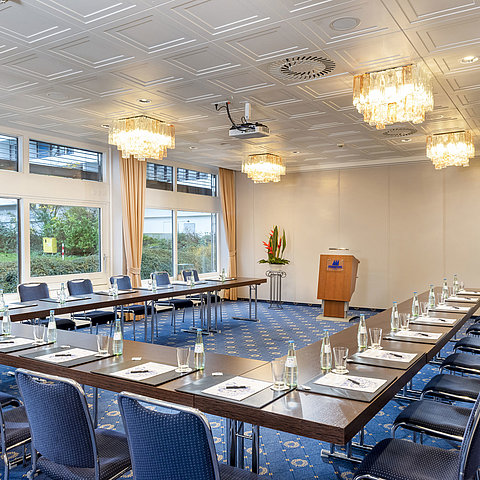 Der Salon Lübeck im Maritim Hotel Kiel, ein moderner Konferenzraum mit U-förmiger Bestuhlung, großen Fenstern und Kronleuchtern.