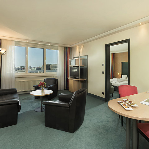 Wohnzimmerbereich der Superior Suite im Maritim proArte Hotel Berlin mit Sitzbereich und Blick aus dem Fenster.