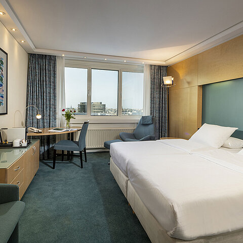 Modern eingerichtetes Superior-Zimmer im Maritim proArte mit großem Bett, Schreibtisch, Kunstwerk und Blick auf die Stadt.