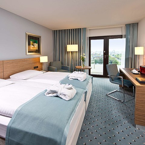 Superior Zimmer im Maritim Hotel Darmstadt mit stilvollem Design, Schreibtisch, Sitzecke und Doppelbett mit Bademänteln.
