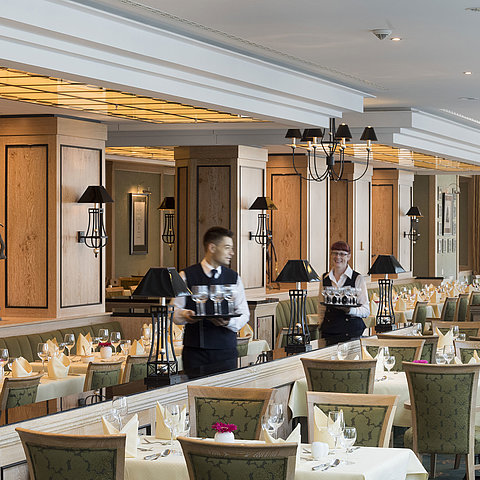 Restaurant 'Wintergarten' im Maritim Hotel Dresden mit gedeckten Tischen und freundlichem Servicepersonal.