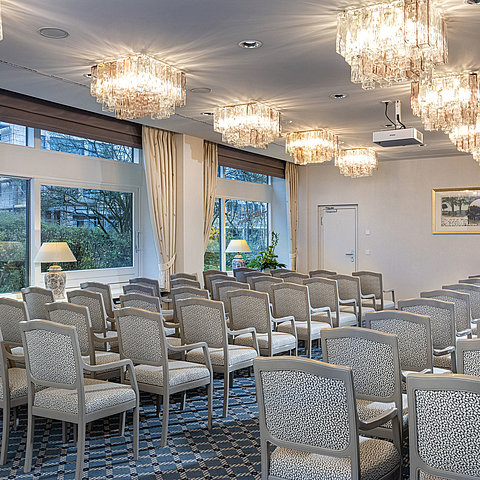 Salon Helsinki im Maritim Hotel Kiel, Konferenzraum mit Stuhlreihen, Kronleuchtern und großen Fenstern mit Blick ins Grüne.