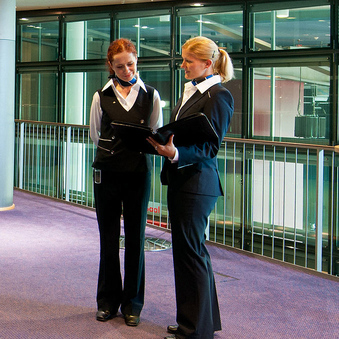  Foyer im Maritim Hotel Dresden mit zwei Mitarbeitenden in Uniform, Stehtischen und einer Obststation.