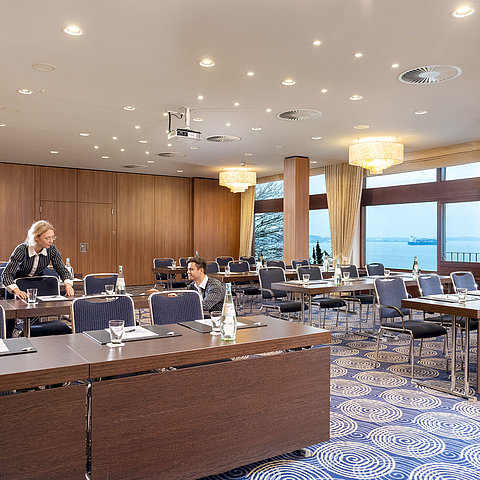 Saal Kiel im Maritim Hotel Kiel, großer Konferenzraum mit Meerblick, freundliches Personal richtet die Tische ein.