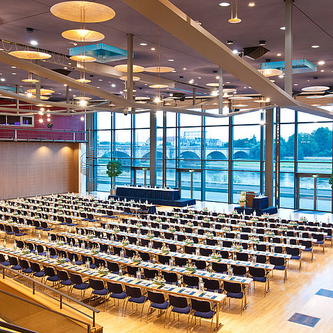 Großer Konferenzsaal im Maritim Hotel Dresden mit Reihen blauer Stühle und Blick auf die Elbe.
