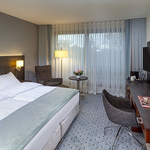 Modernes Superior-Doppelzimmer im Maritim Bremen mit Sitzbereich, Schreibtisch und großem Fenster für natürliche Beleuchtung.