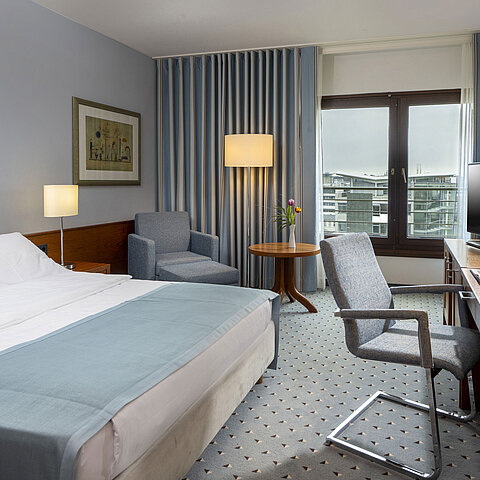 Comfort-Doppelzimmer im Maritim Hotel Darmstadt mit gemütlicher Sitzecke, modernem Schreibtisch und Blick auf die Stadt.